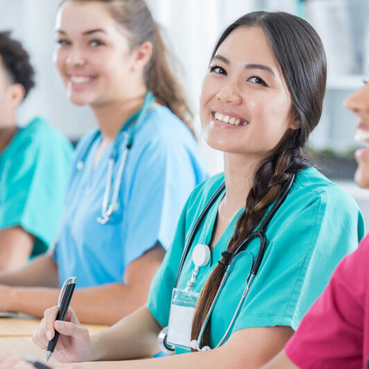 Confident Asian female medical or nursing student smiles in the classroom.